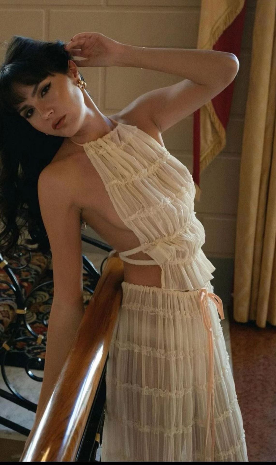 Woman wearing a white lace dress standing indoors.